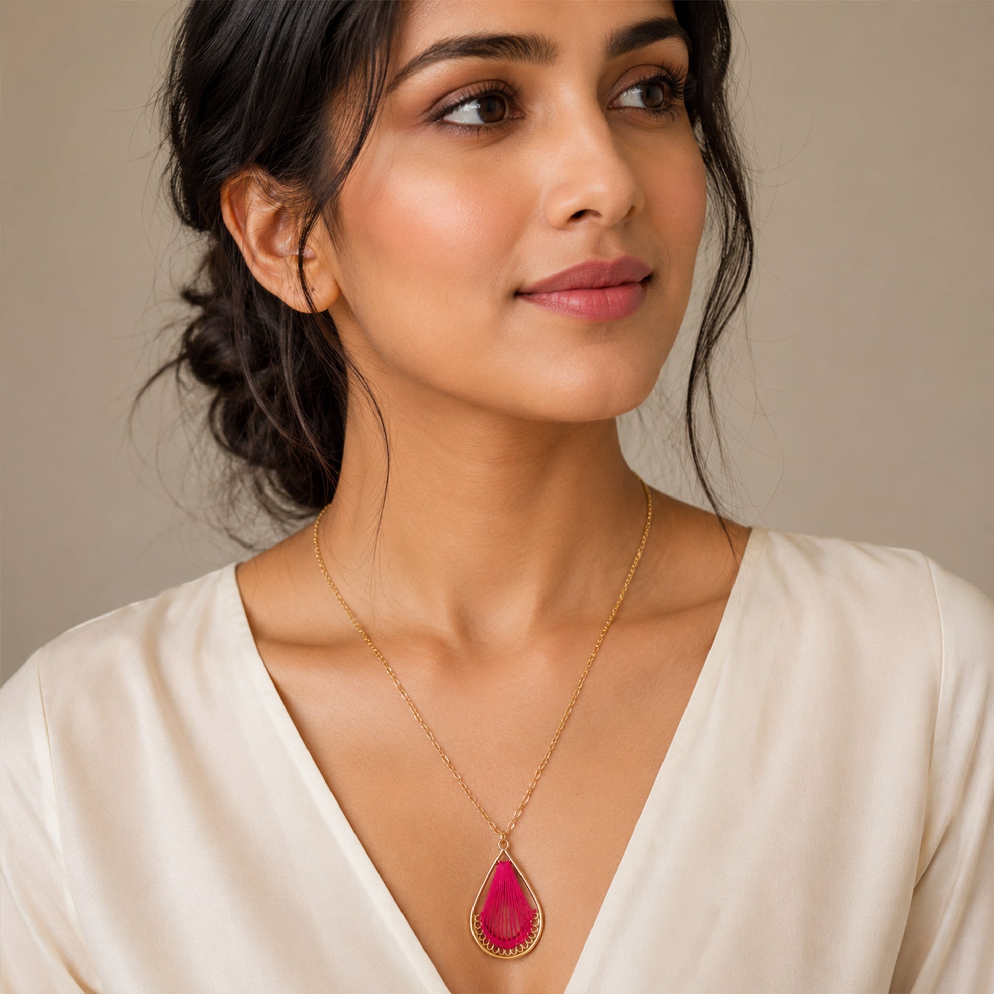 Close-up view of pink thread pendant with gold teardrop frame