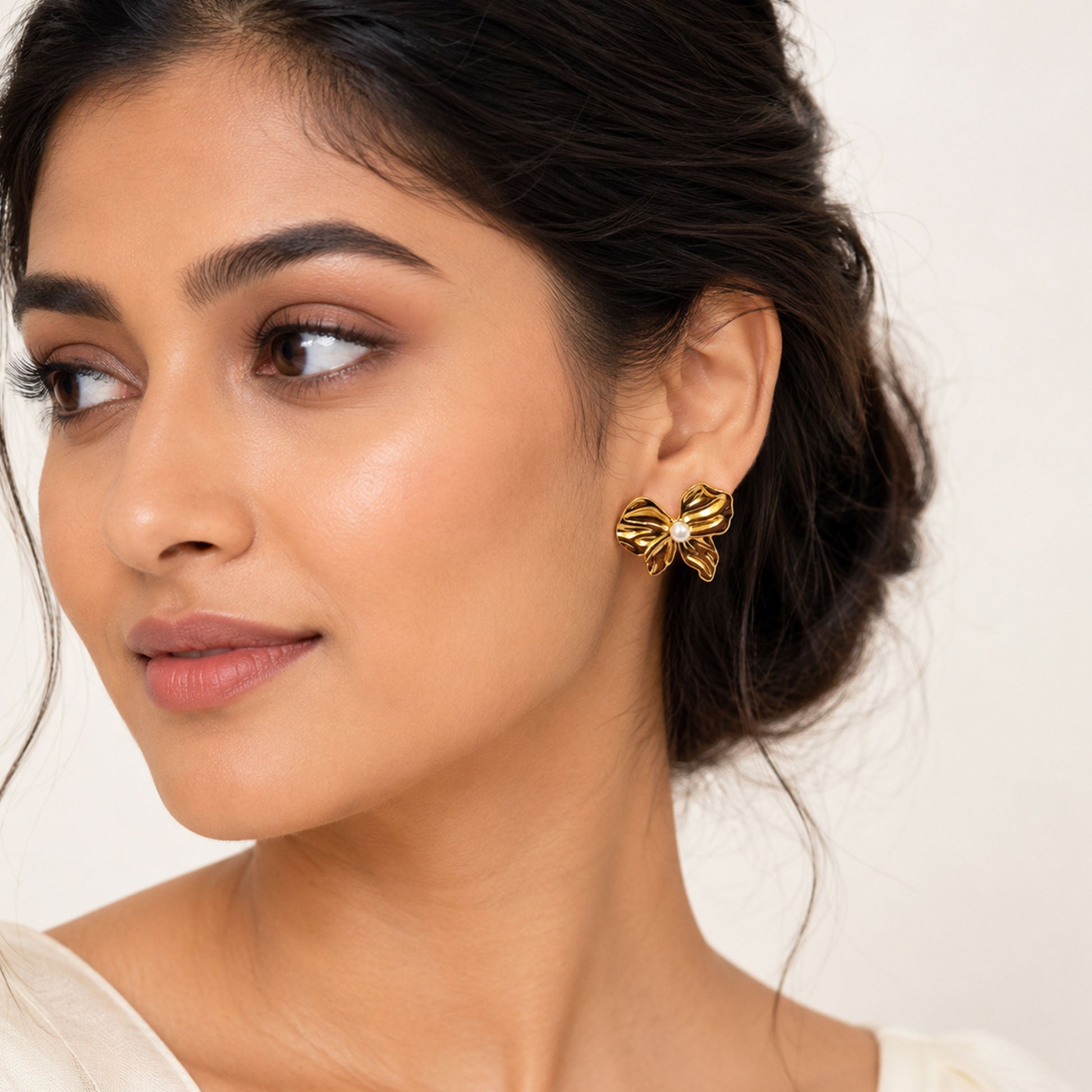 Close-up view of gold bow earrings with pearl centerpiece