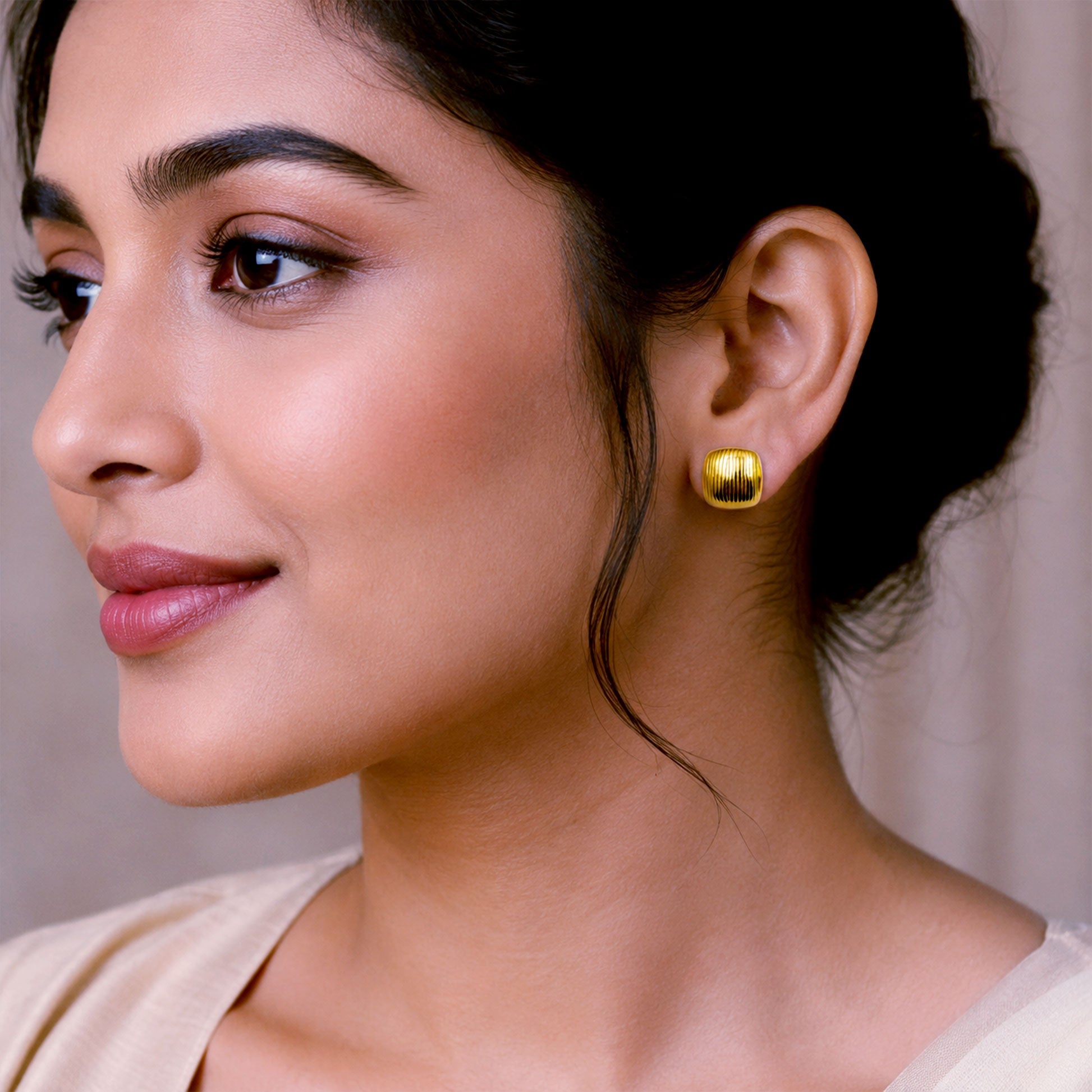 Close-up view of gold square earrings with vertical ribbed texture