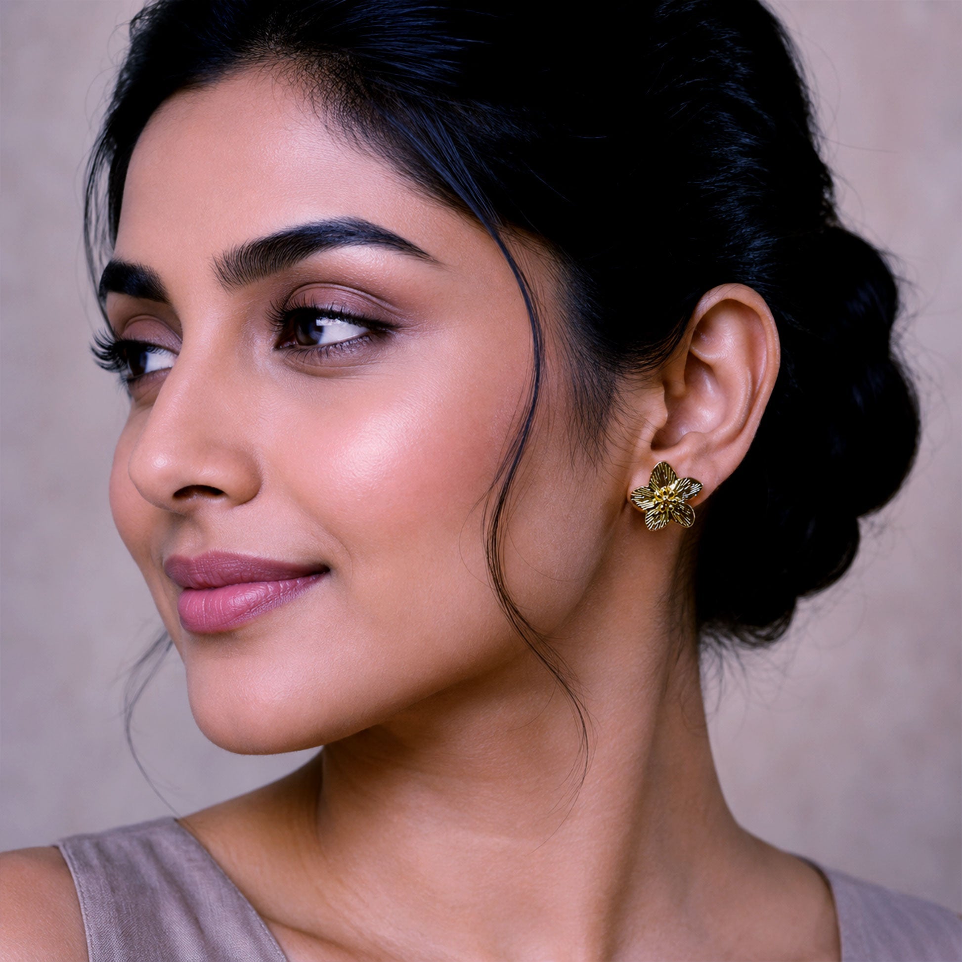 Close-up view of gold floral earrings with engraved petal detailing