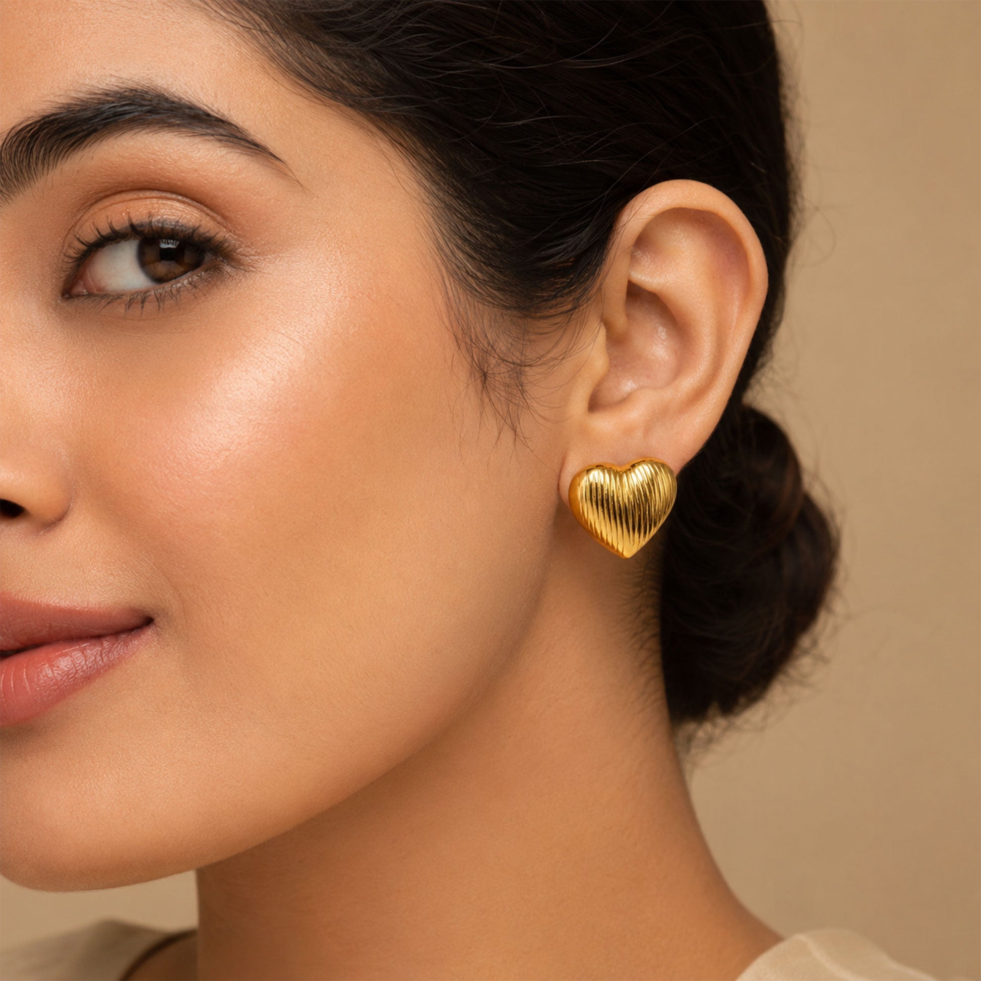 Close-up view of gold heart earrings with ribbed detailing