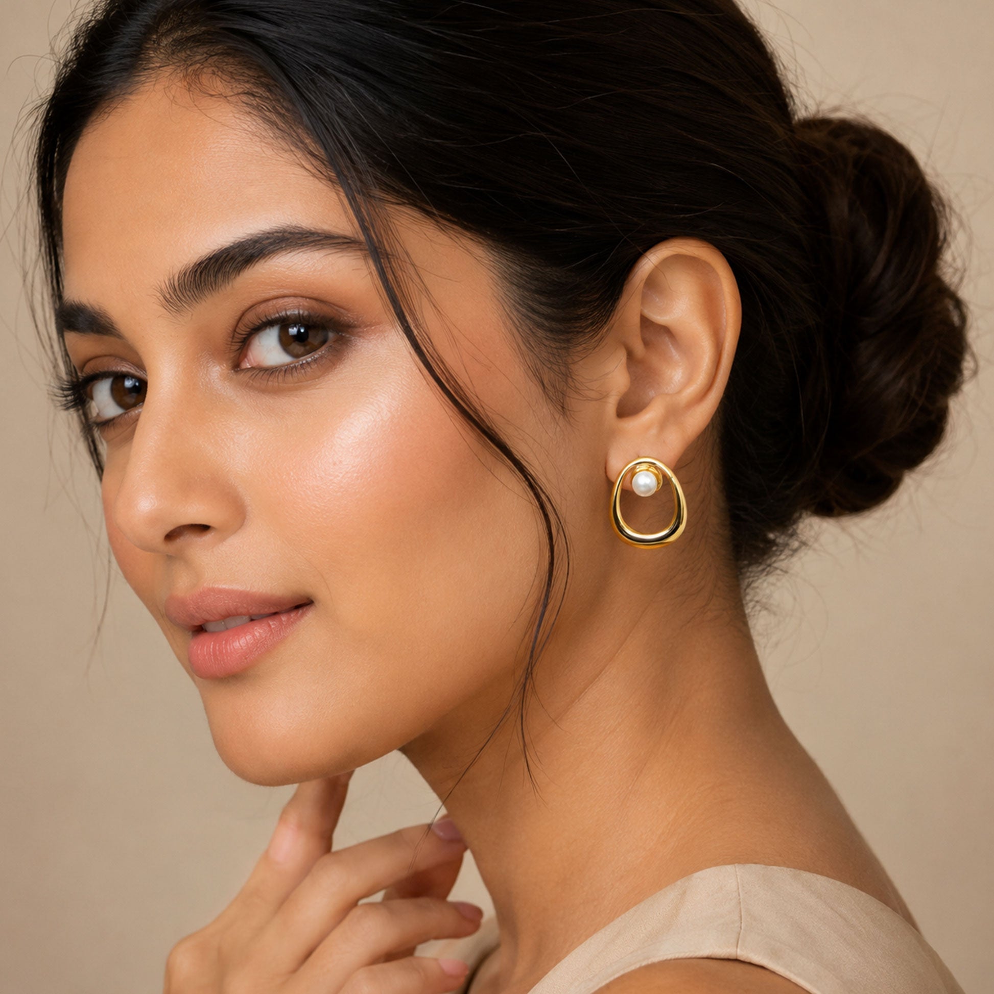 Close-up view of gold oval earrings with white pearl accent