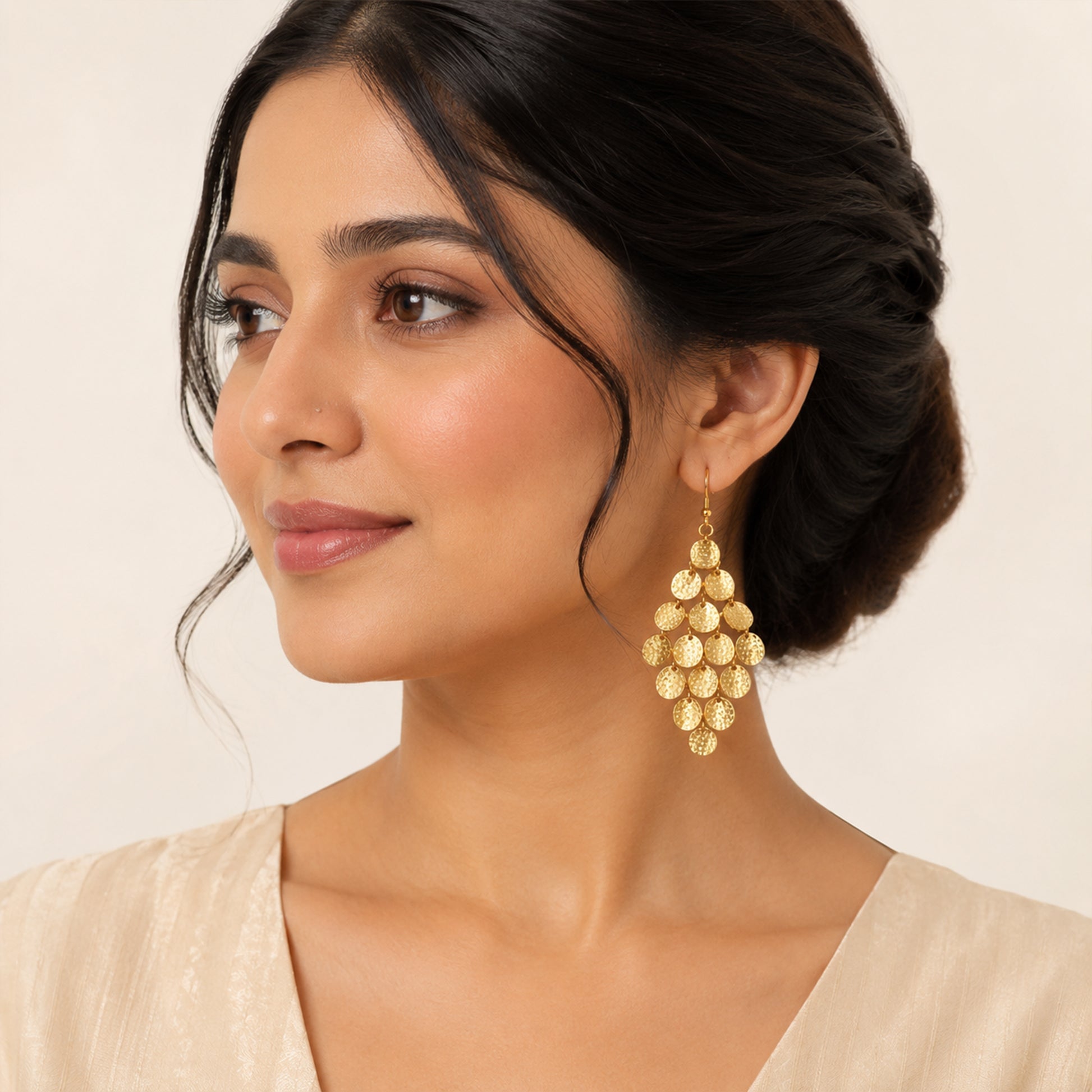 Close-up view of gold cascading disc earrings with textured finish