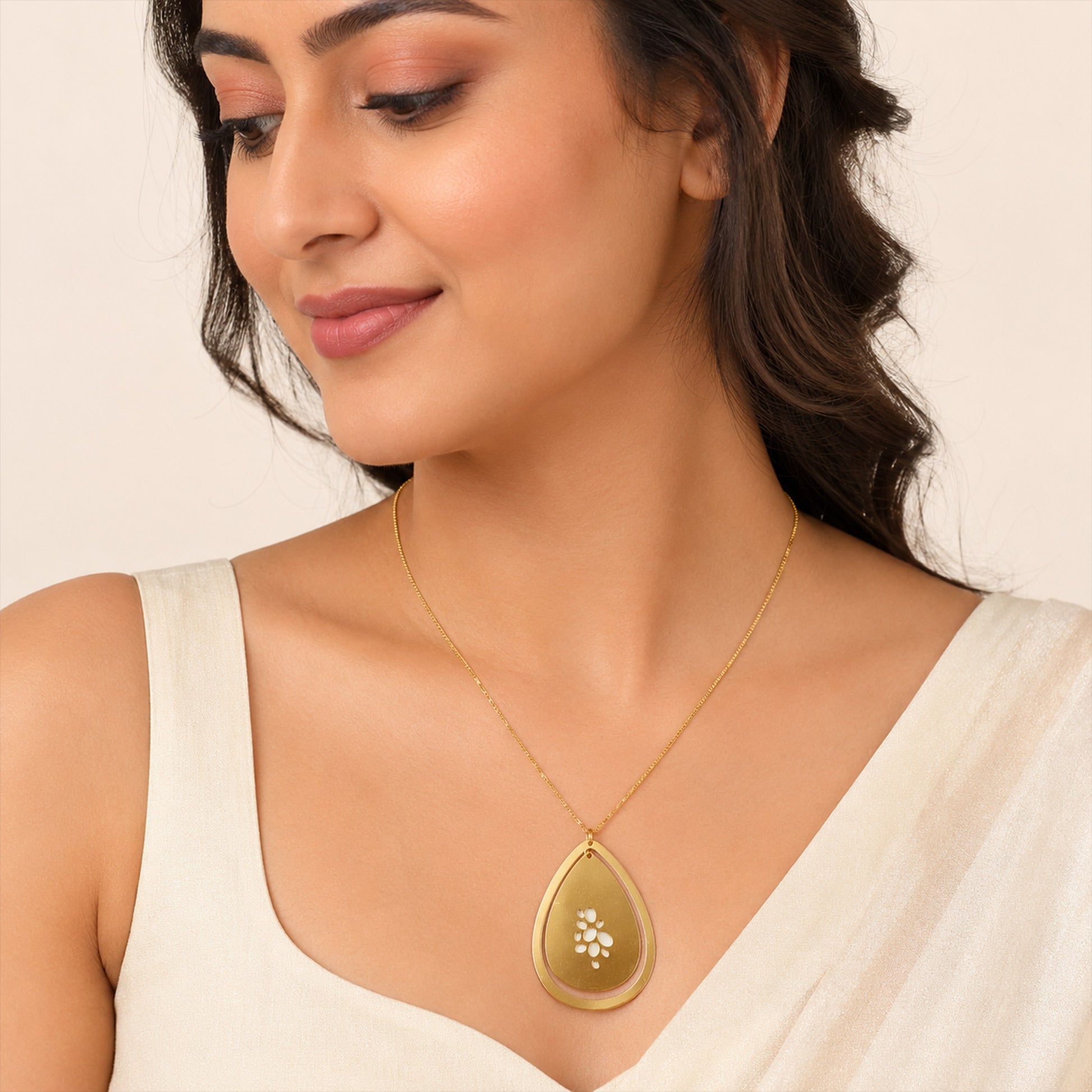 Close-up view of gold teardrop necklace with floral cutout design