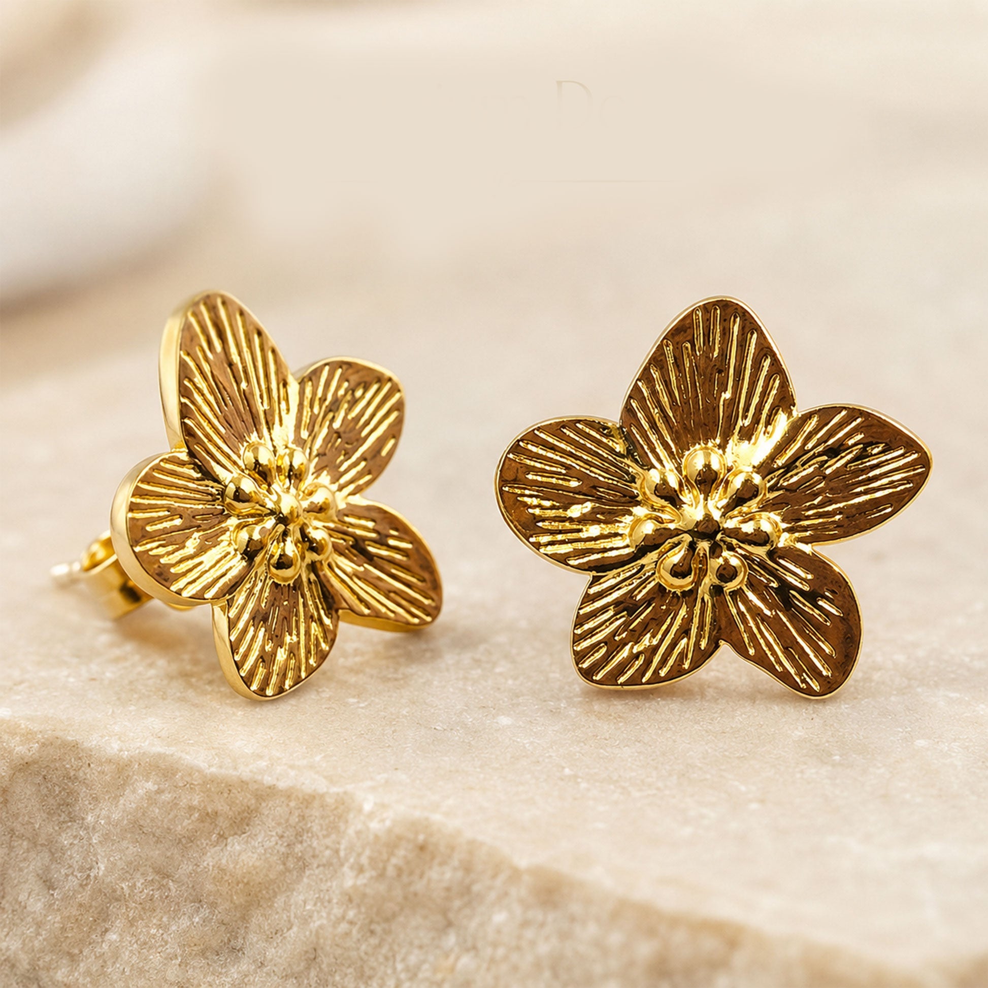 Detailed view of sculpted gold floral stud earrings