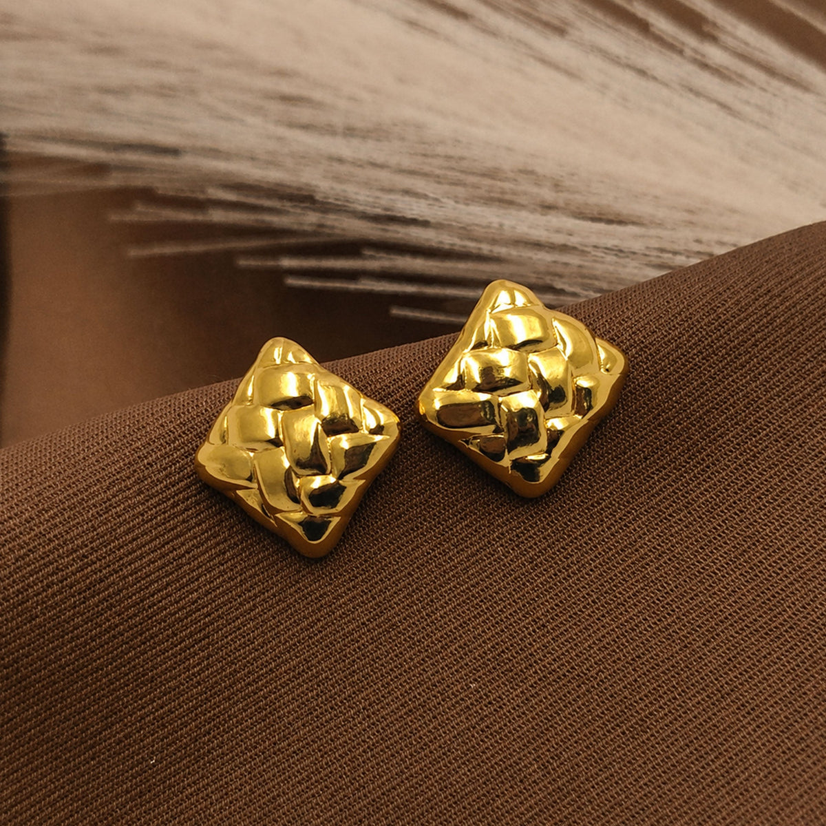 Detailed view of sculpted gold square stud earrings