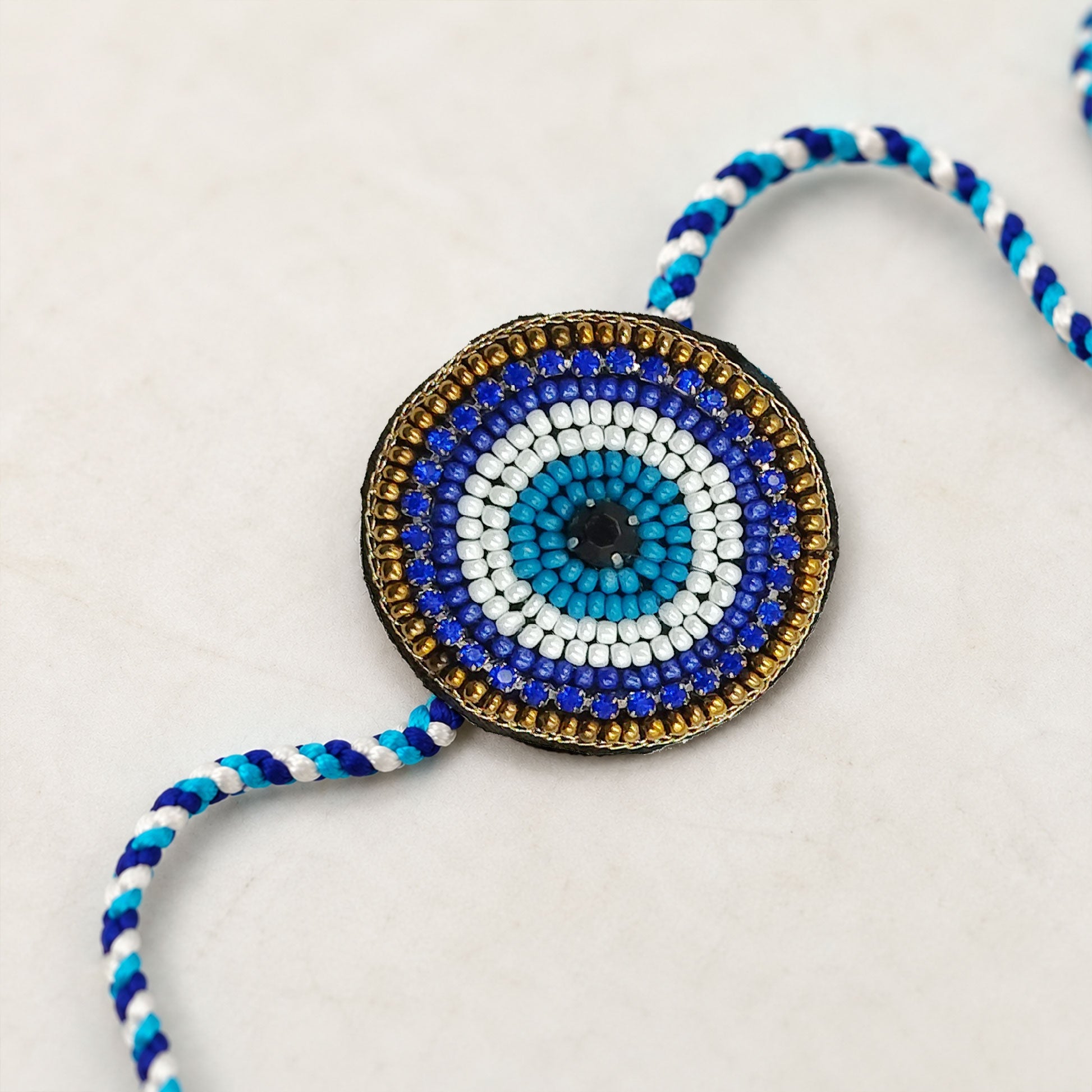Close-up view of blue evil eye rakhi with bead detailing