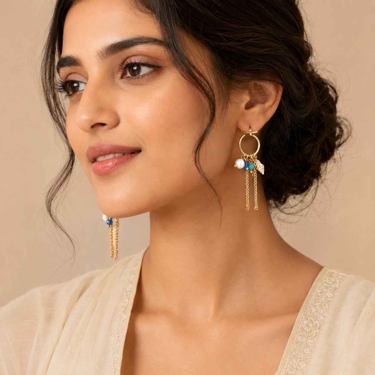 Close-up view of gold hoop earrings with pearl and shell charms