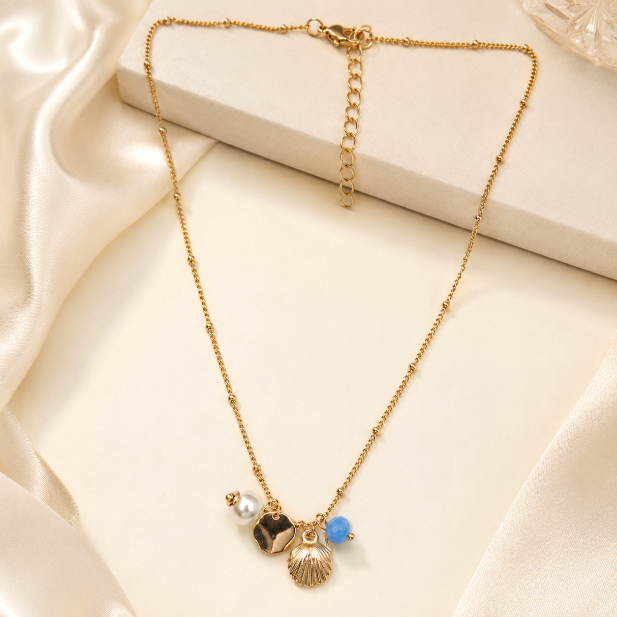 Detailed view of gold shell pendant with pearl and coin charms