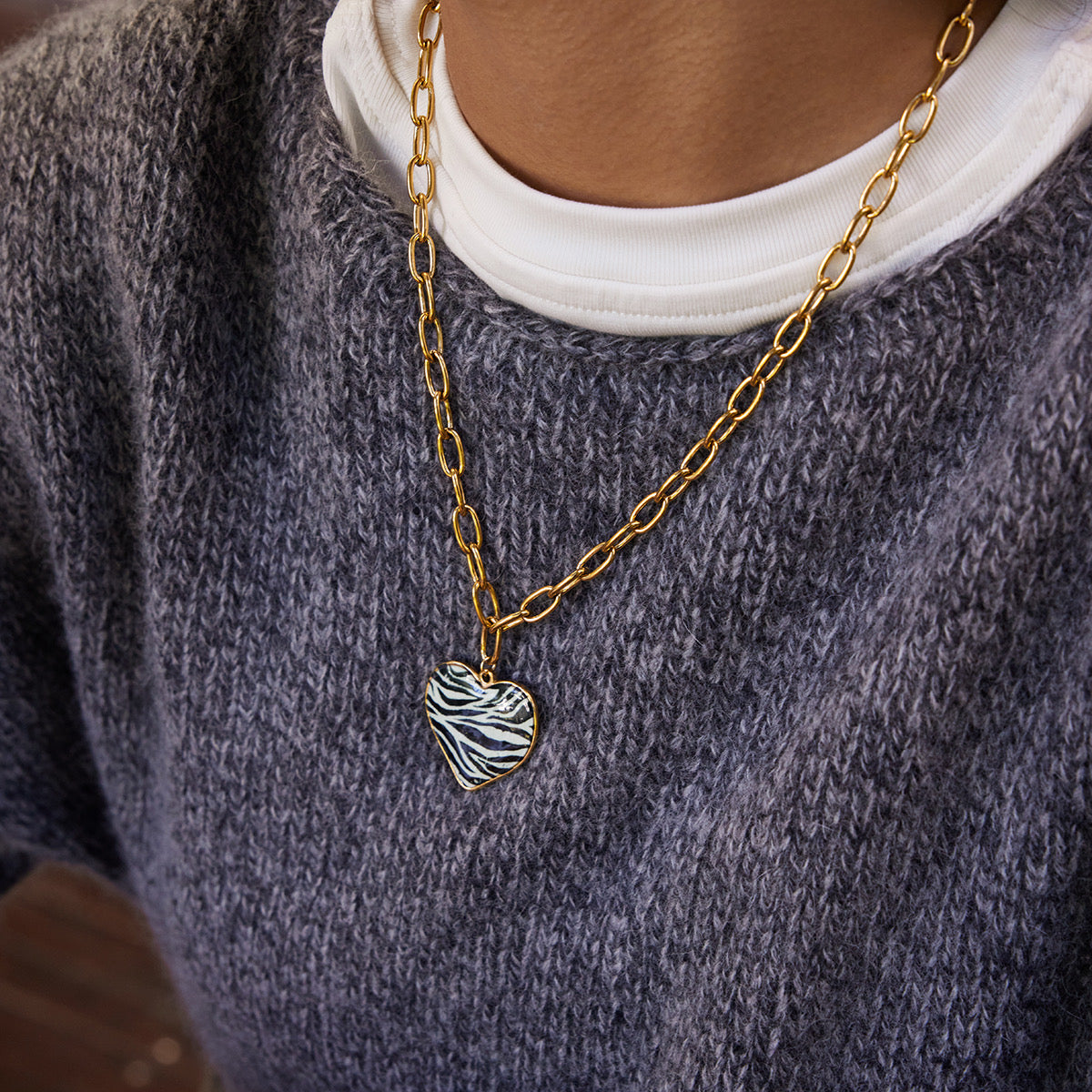 Styled view of zebra heart necklace �? 18k gold-plated bold pendant for statement evening wear.