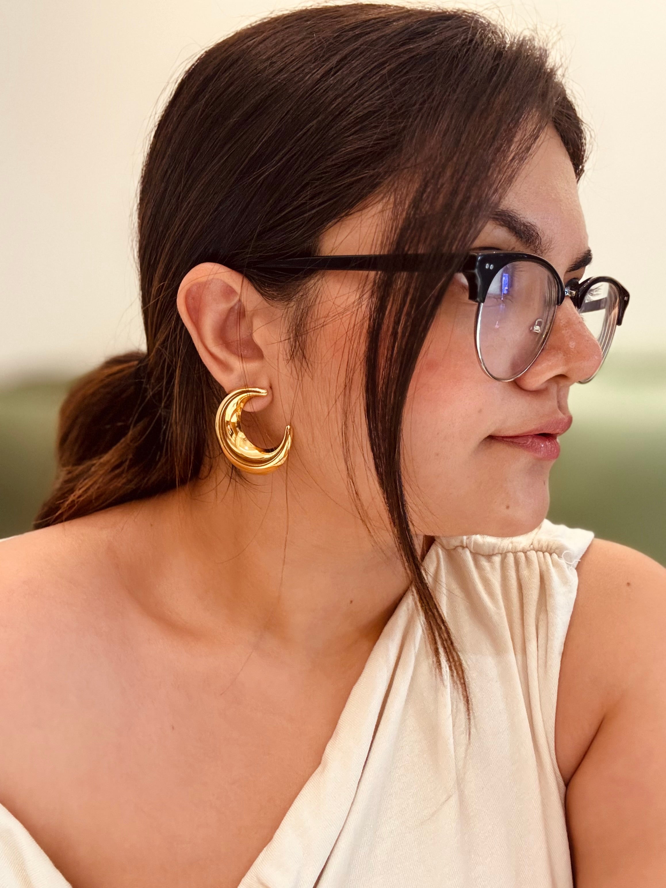 Moon studs displayed �? 18k gold-plated bold celestial moon hoops for evening looks.