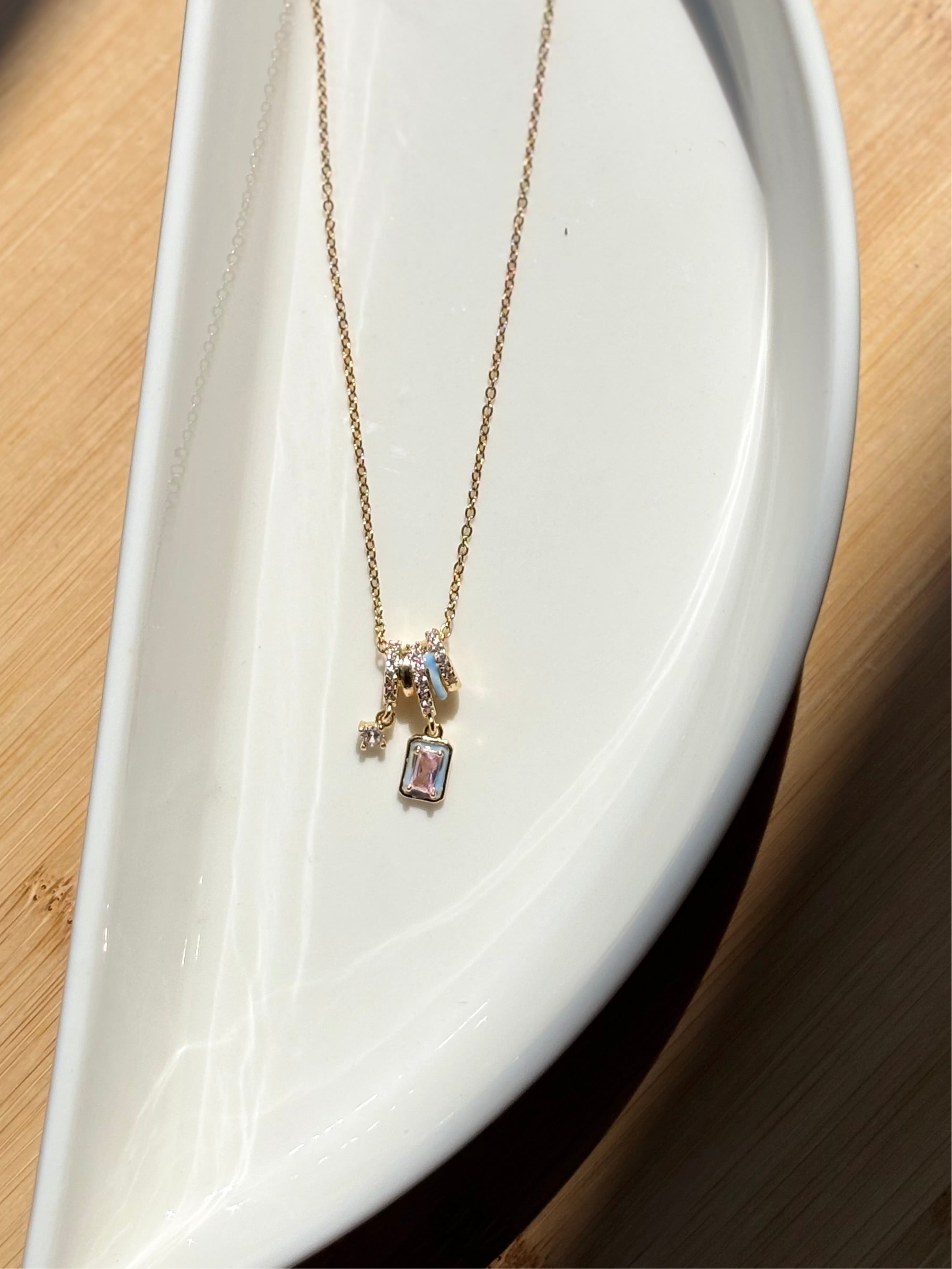 Pastel Bloom necklace displayed with charms visible �? layerable with chokers and longer chains for styling.