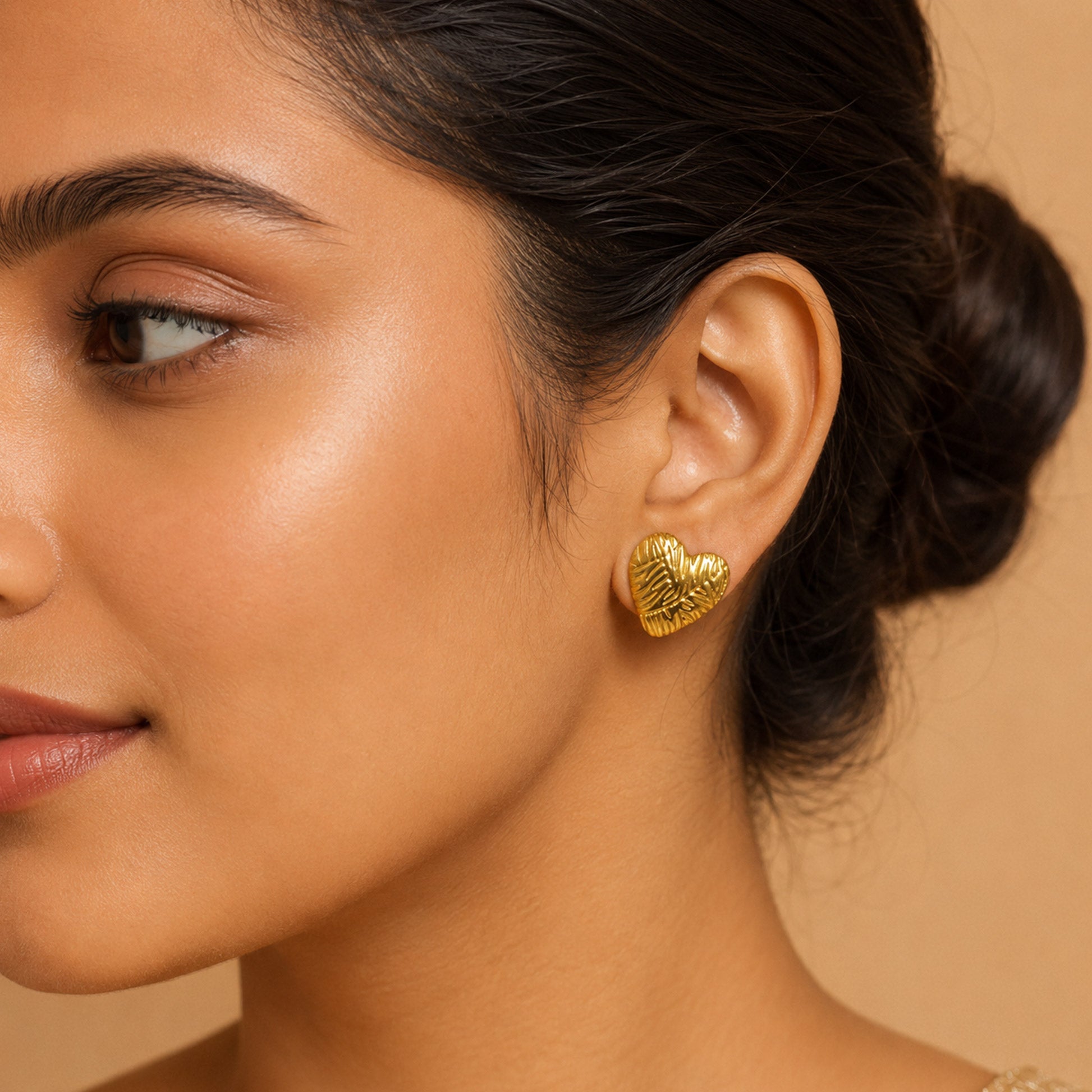 Close-up view of gold heart earrings with artistic texture