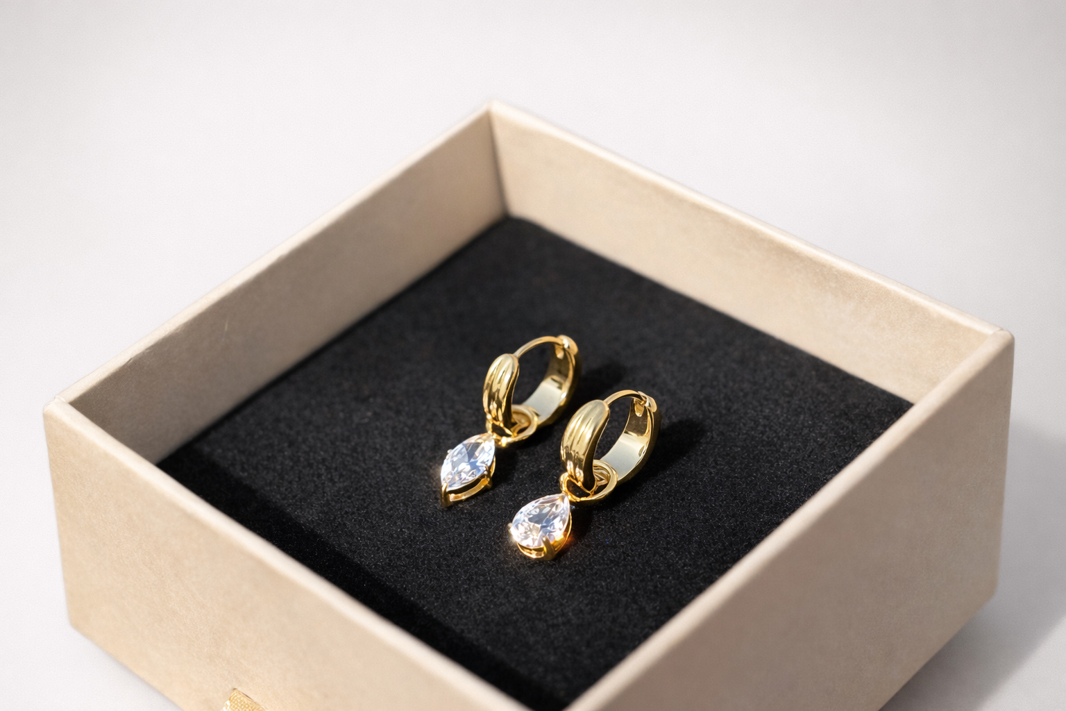 Close-up of Noor crystal huggie earrings �? 18k gold-plated sparkle teardrop huggies for evening styling.
