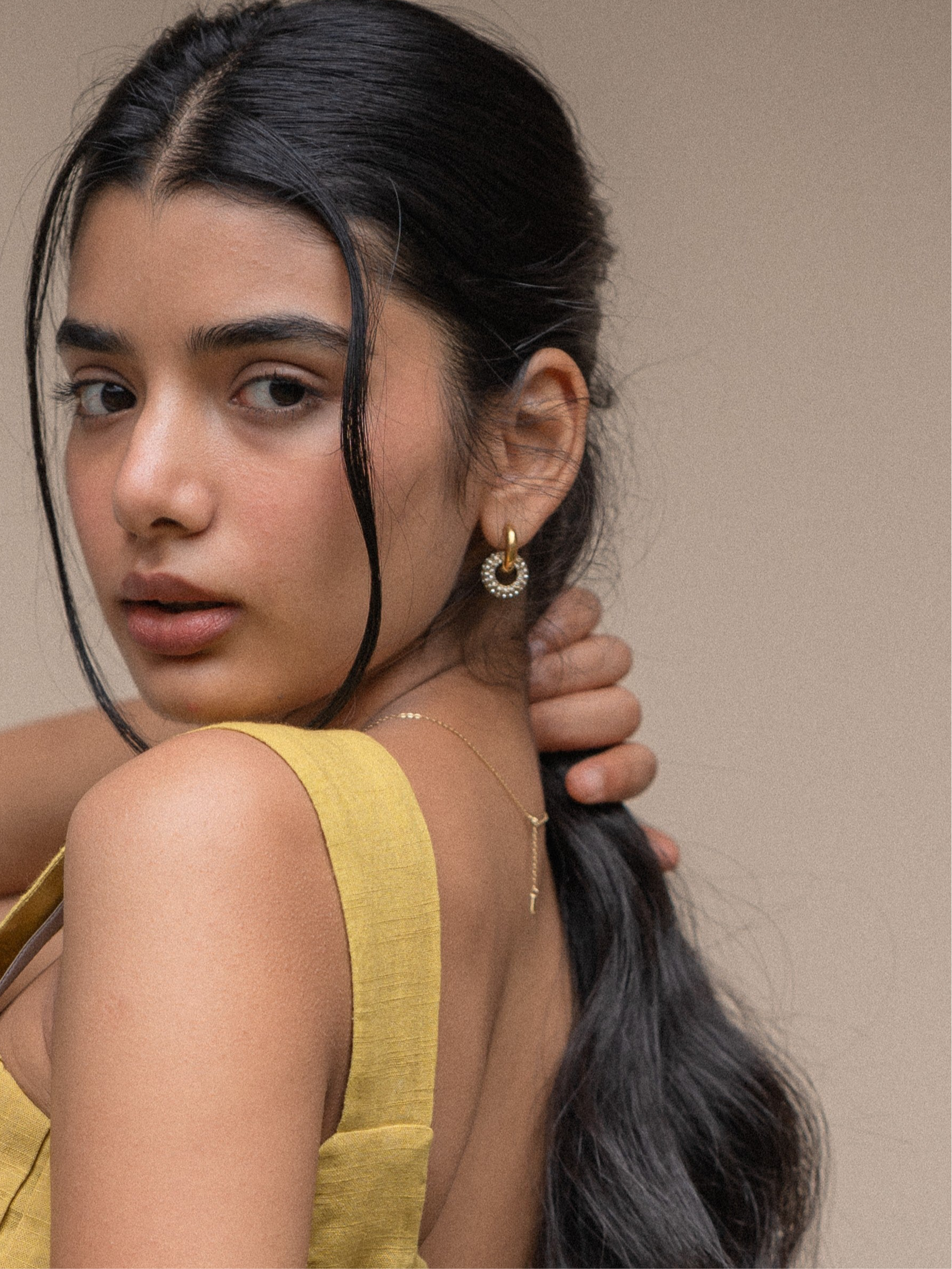 Model wearing gold-plated sparkle huggie earrings �? day-to-night hoops styled for office and casual occasions.