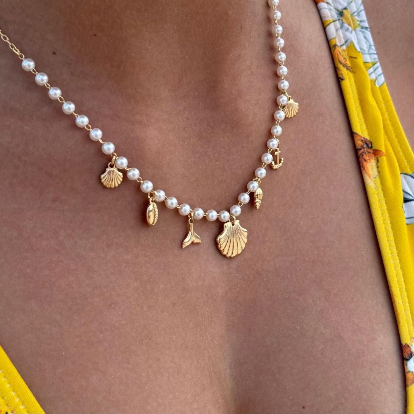 Close-up of Cresta drop earrings �? 18k gold-plated sea-theme marine-charm pearl drops for summer wear.