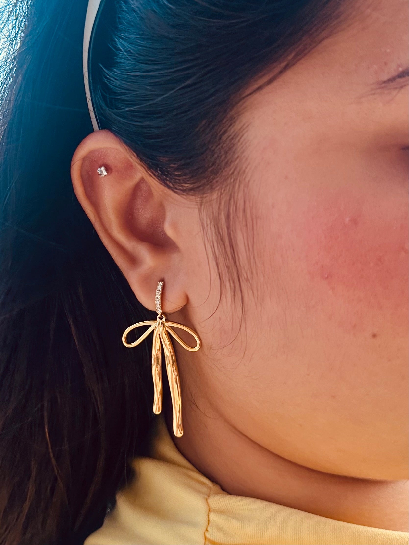 Close-up of Bow earrings �? 18k gold-plated chic white-stone bow statement drops for festive looks.