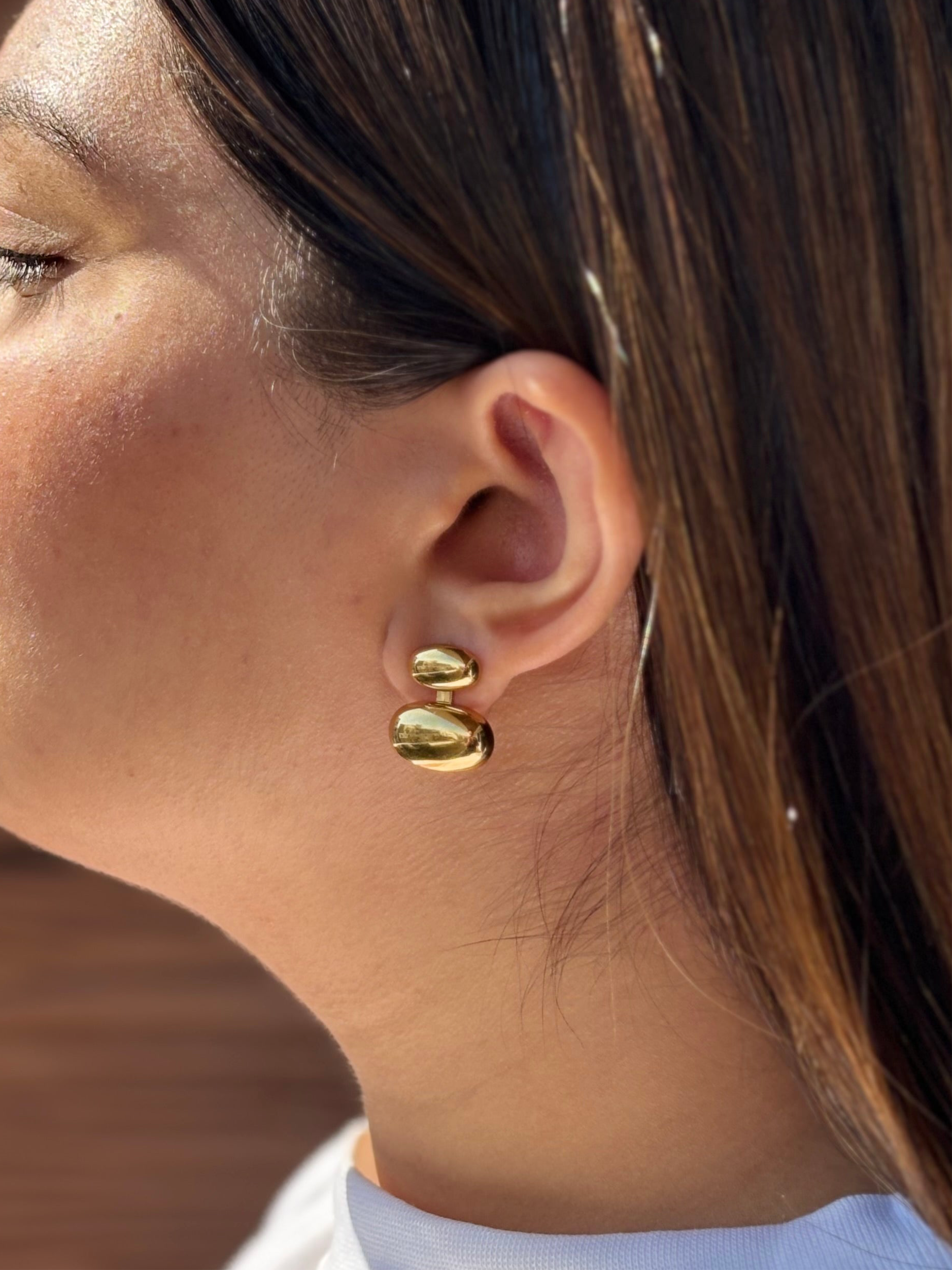 Pebble stud earrings shown styled flat �? versatile 18k gold-plated studs for everyday and evening wear.