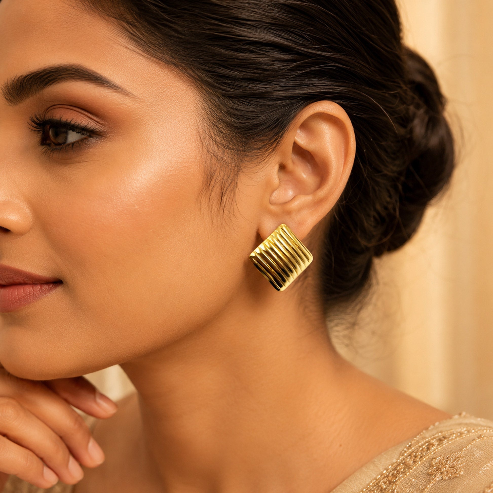 Woman wearing gold ribbed square stud earrings for elegant look