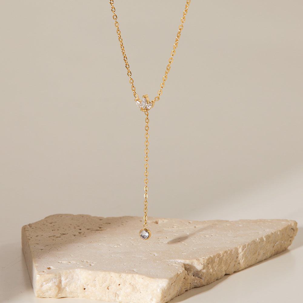 Detail shot of Stella lariat necklace �? elegant white stone leaves and ball drop on 18k gold-plated stainless steel.