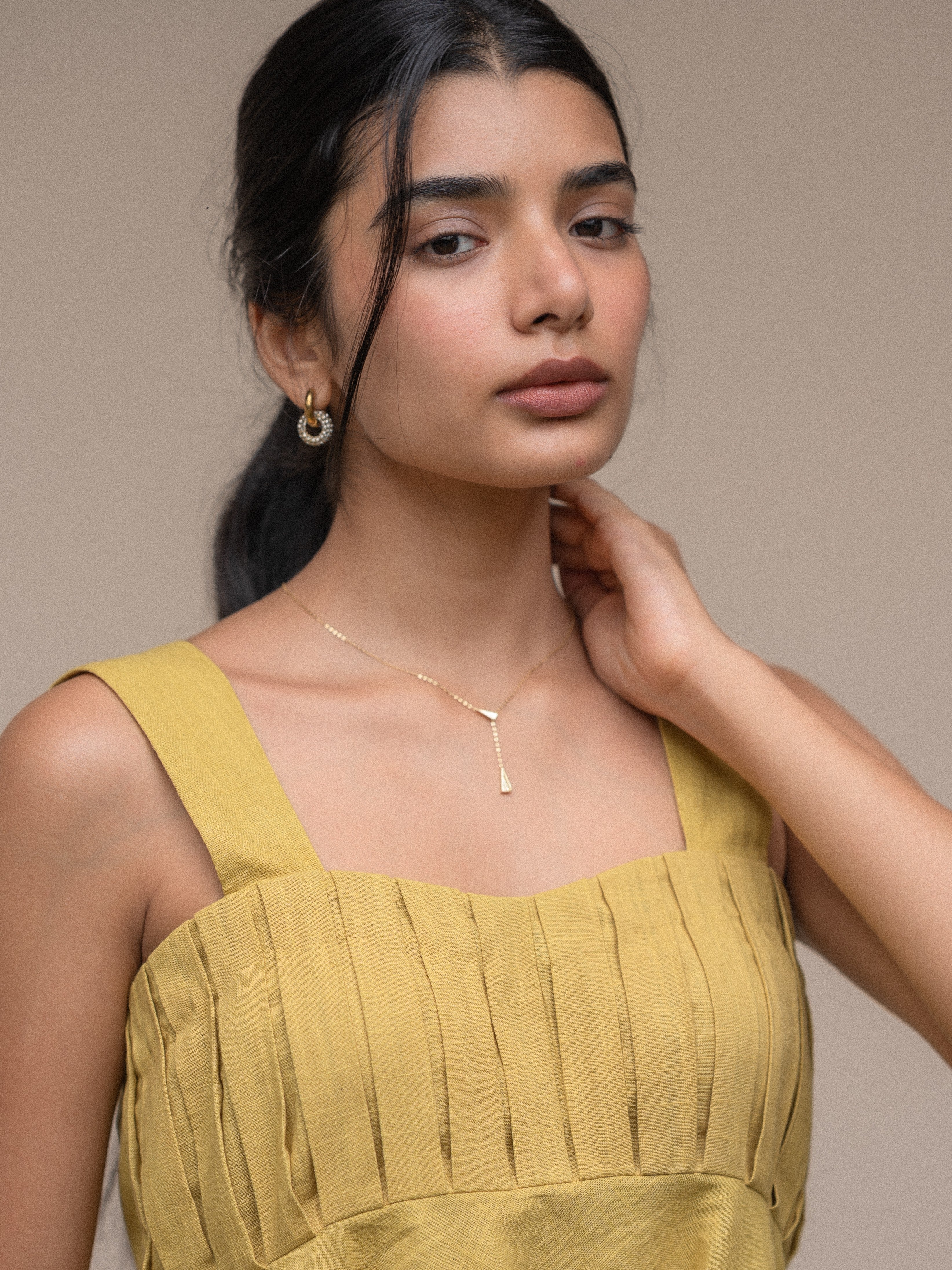 Detail of 18k gold-plated huggie earrings �? anti-tarnish, waterproof, lightweight stainless steel base.