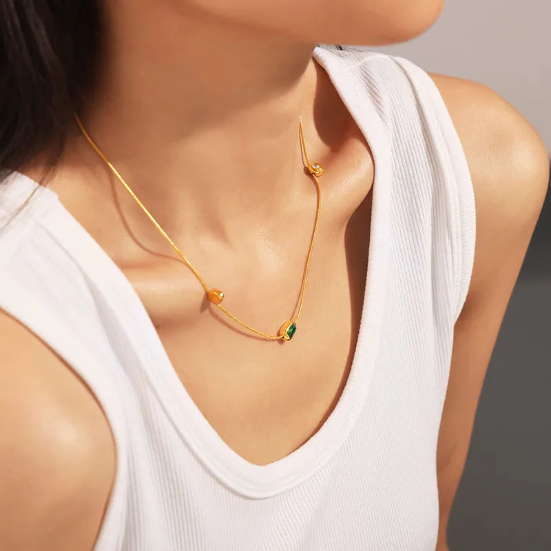 Close-up of Thaira pendant necklace �? 18k gold-plated elegant green pink white stones for evening wear.