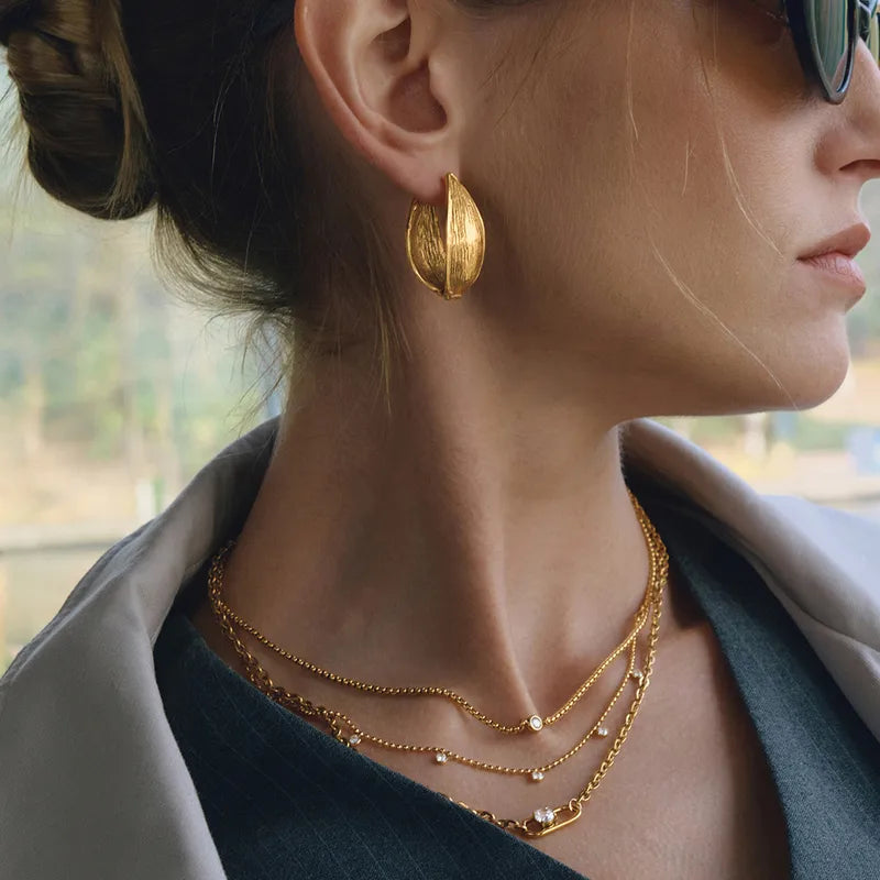 Close-up of Liva gold hoop earrings �? chunky 18k gold-plated hoops, lightweight and waterproof for daily wear.